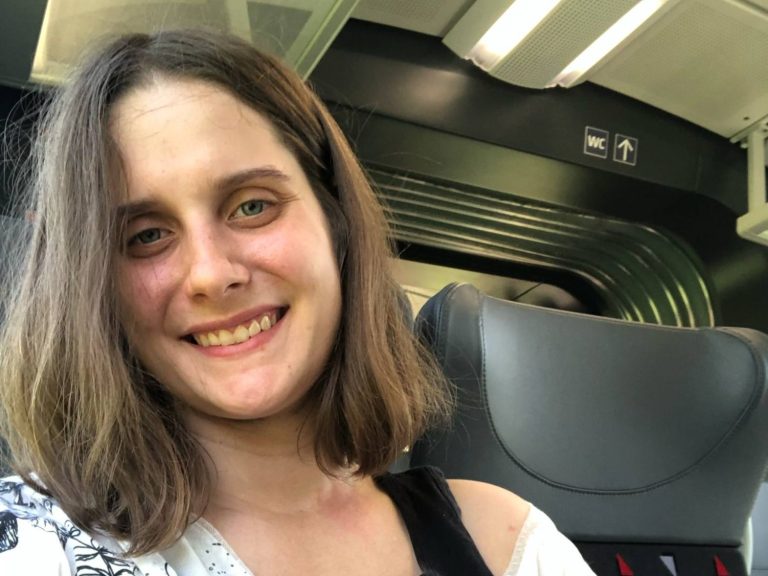 Hund mit braunem und grauem Fell, trägt ein rotes Halsband und schaut nach oben.